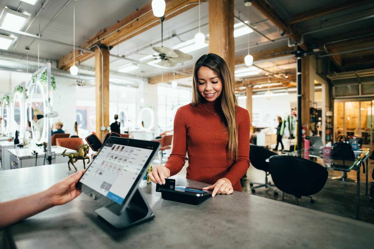 Hand-operated point of sale terminal, and a girl swipes her credit card to pay.